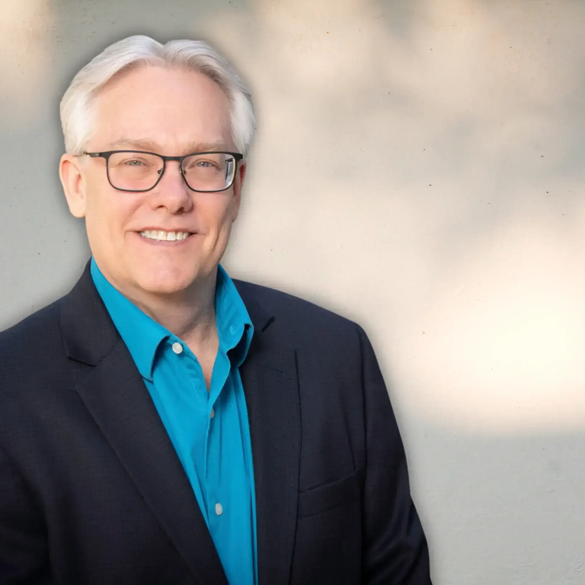 Headshot of Steve, smiling, wearing glasses and a blue shirt with a dark blazer, representing a client testimonial for brand alignment and strategic positioning.