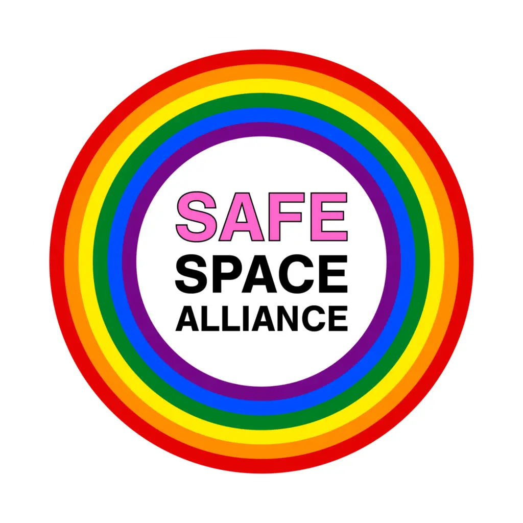 Rainbow circular logo for safe space alliance with concentric rainbow rings around a white center containing the pink and black text 'safe space alliance'